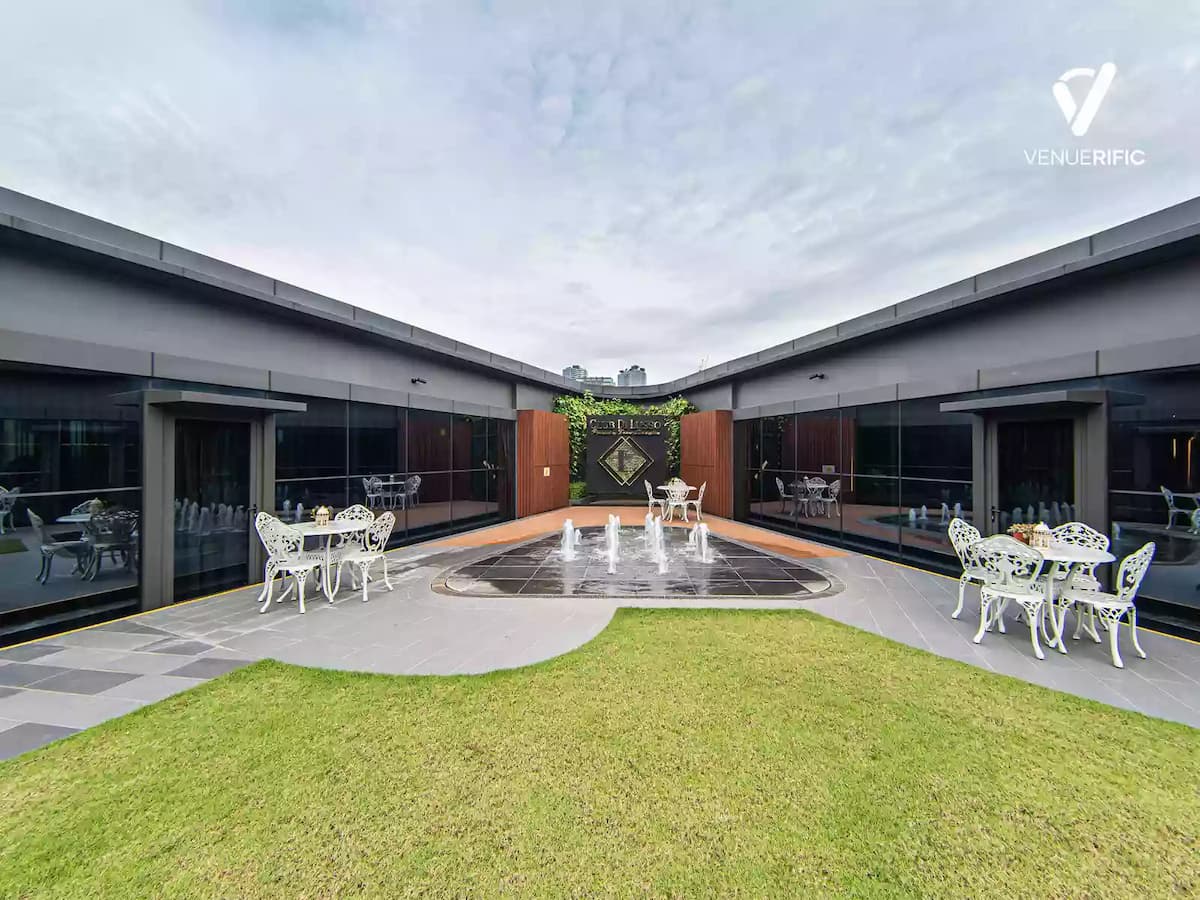 Fountain in the middle of outdoor space with white chairs around tables on the side