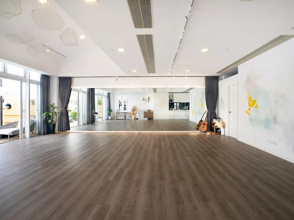 Large spacious room with brown floors and a mirror wall