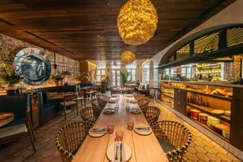 dining area with long wooden tables woven chairs and warm lighting