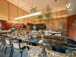 restaurant with marble table cane chairs potted tree and orange tiled walls