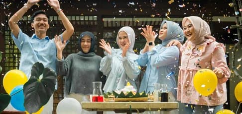 A happy group of friends celebrating with confetti, colorful balloons, and traditional food, illustrating the joy of finding the best place to celebrate birthday in KL for social gatherings.
