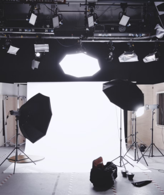 photography studio setup with white backdrop umbrella lights and overhead lighting equipment
