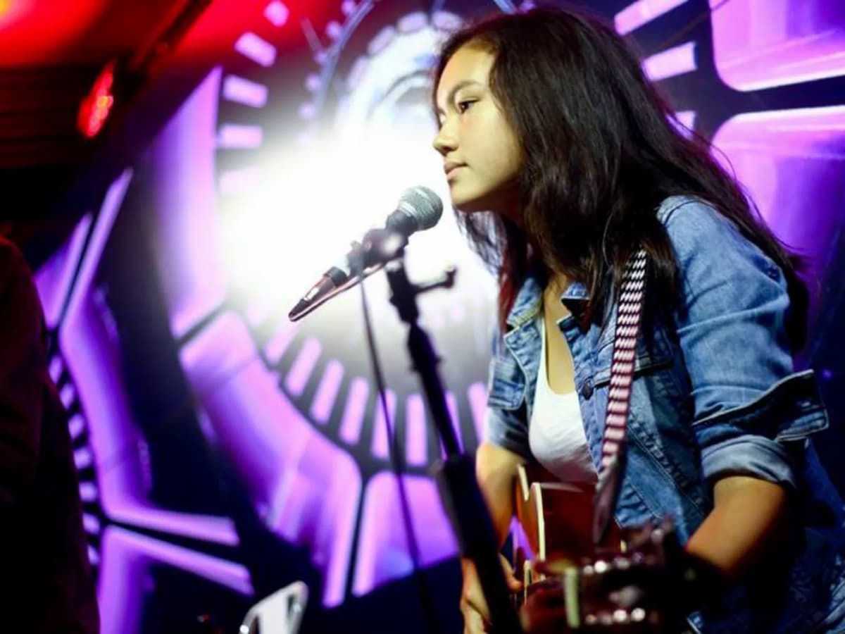 person singing with guitar in concert in the hub event venue