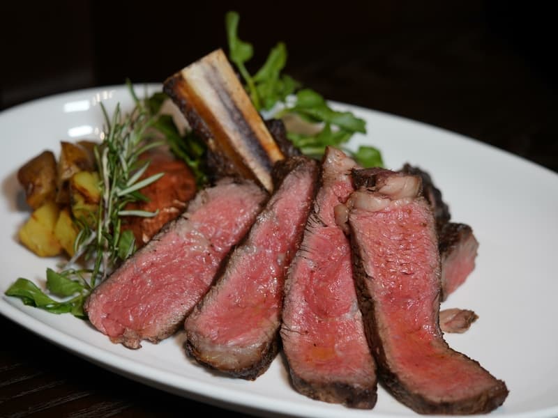 dinner party event venue for rent that serves rare smoked steak served with potato and simple garnish in the top of white plate