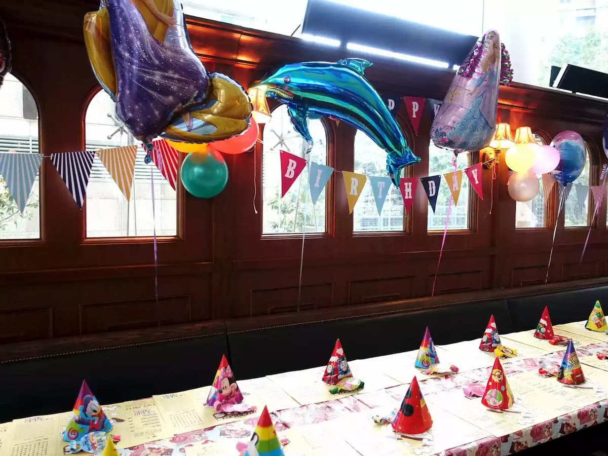 long table setup with balloon decoration and kids birthday party hat on the table