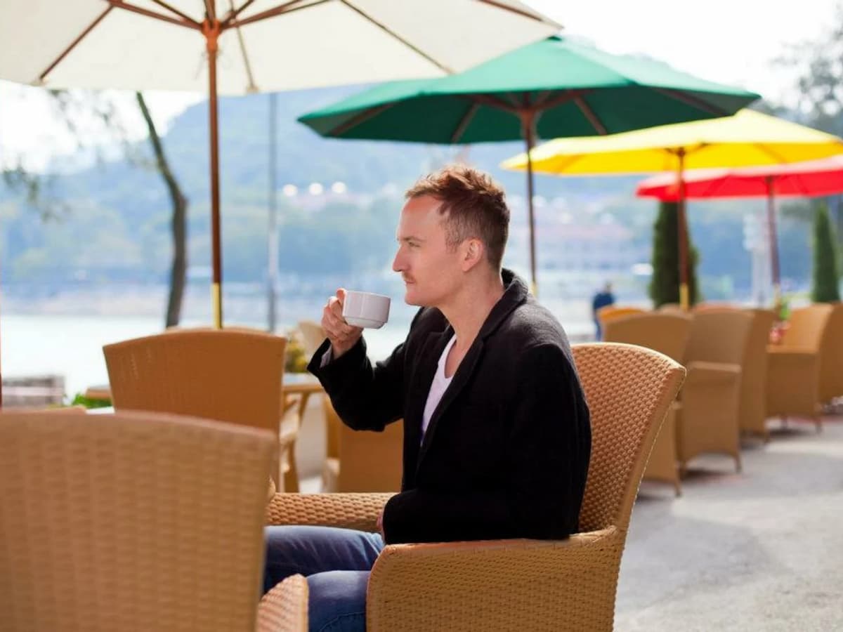 a man is enjoying his coffee at the outdoor area with a panoramic view of silvermine bay