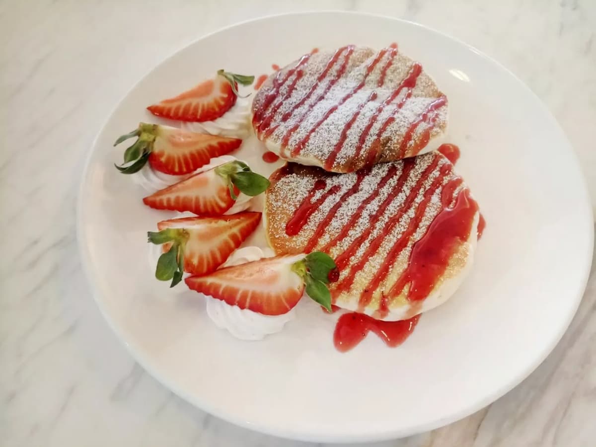 two strawberry pancakes with strawberry slices and jam on the top of the pancakes