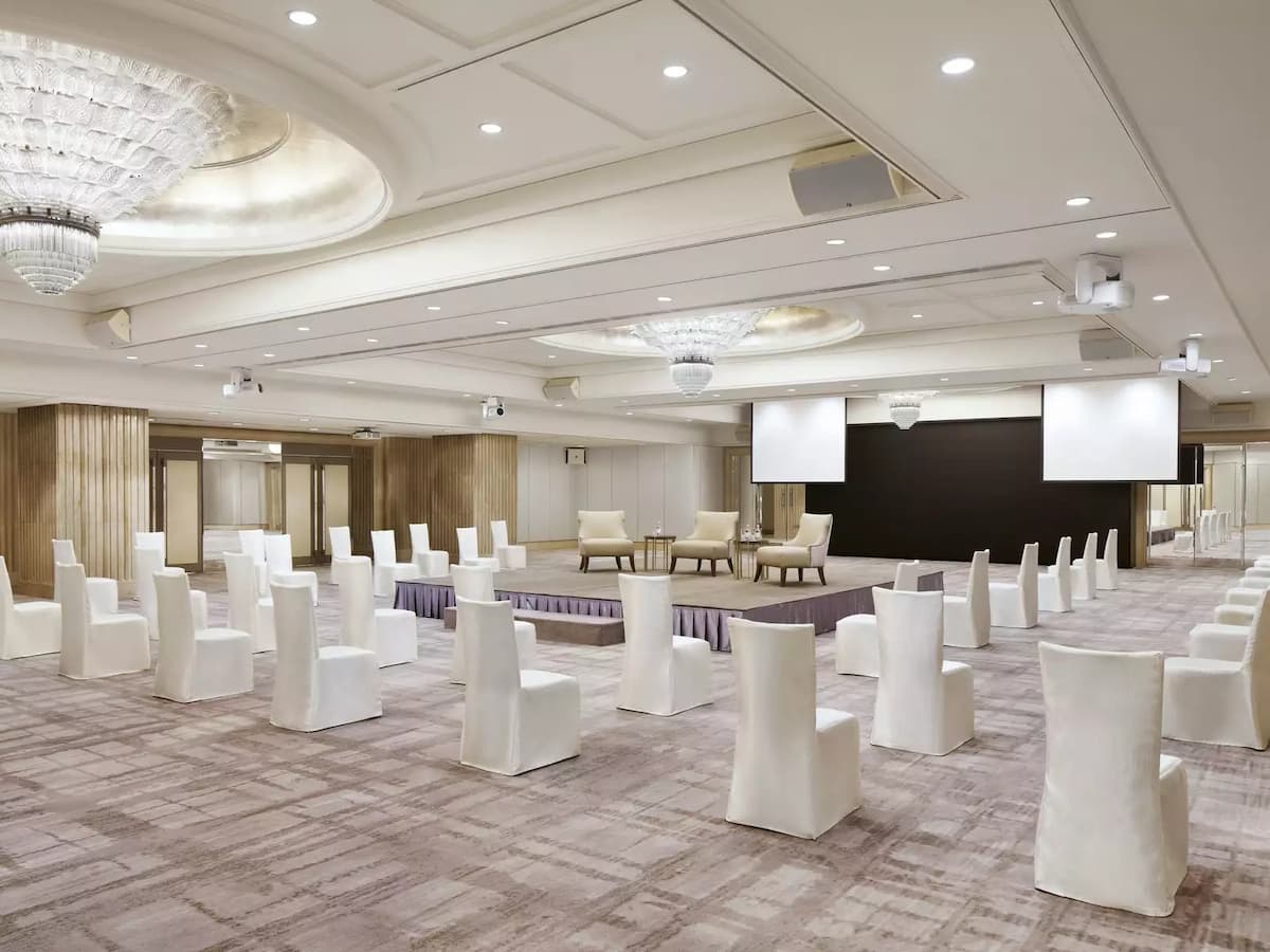 a spacious ballroom with white chairs and a stage