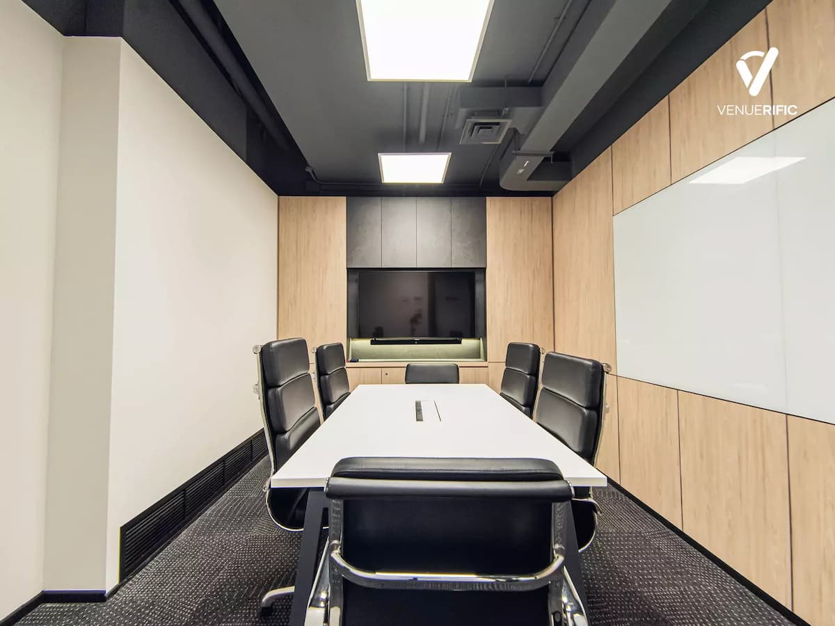 a meeting room with black office chairs and white table
