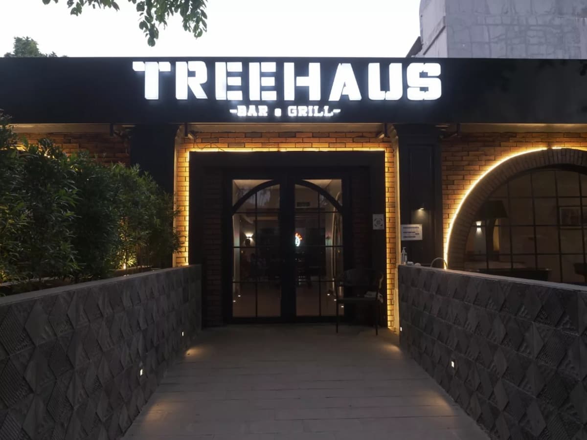 outdoor patio with a lit "treehaus bar and grill" signage