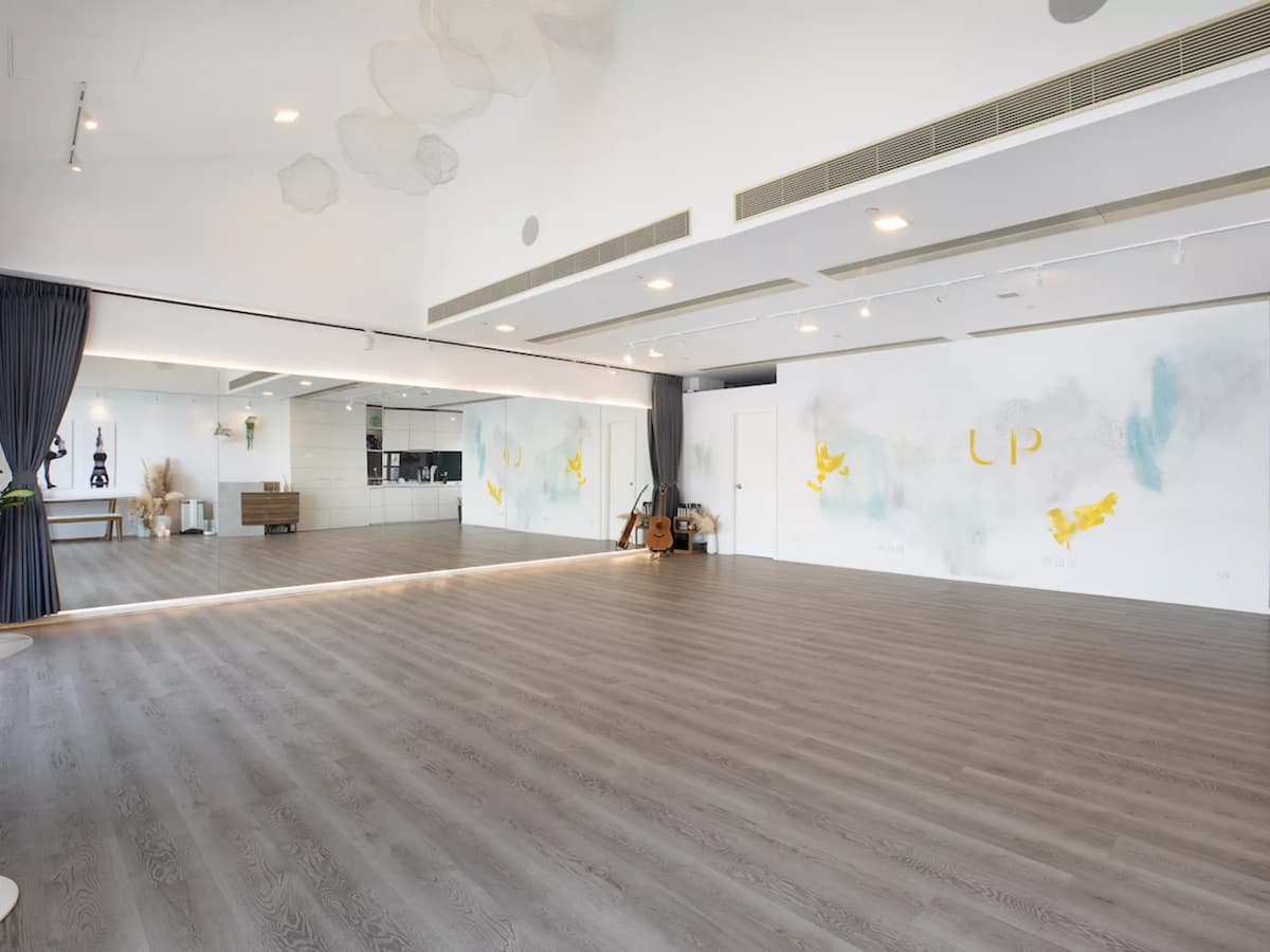 Side view of spacious room with brown wooden floors and mirrored wall