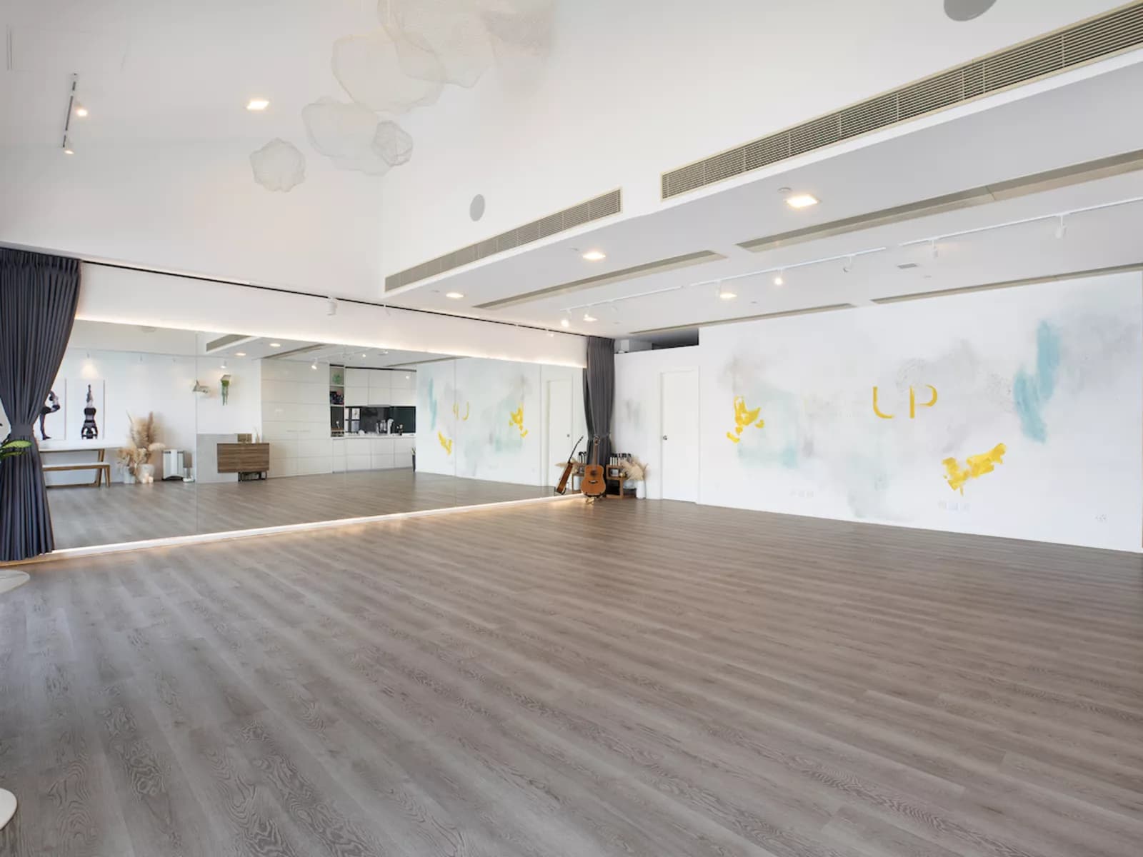 Side view of spacious room with brown wooden floors and mirrored wall