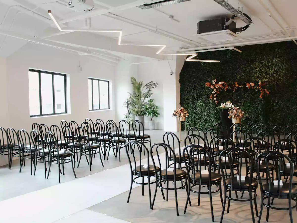 intimate wedding ceremony event venue for rent in singapore with function hall with lush green wall and floral arbour and white carpet walkway and chairs good for 50 pax