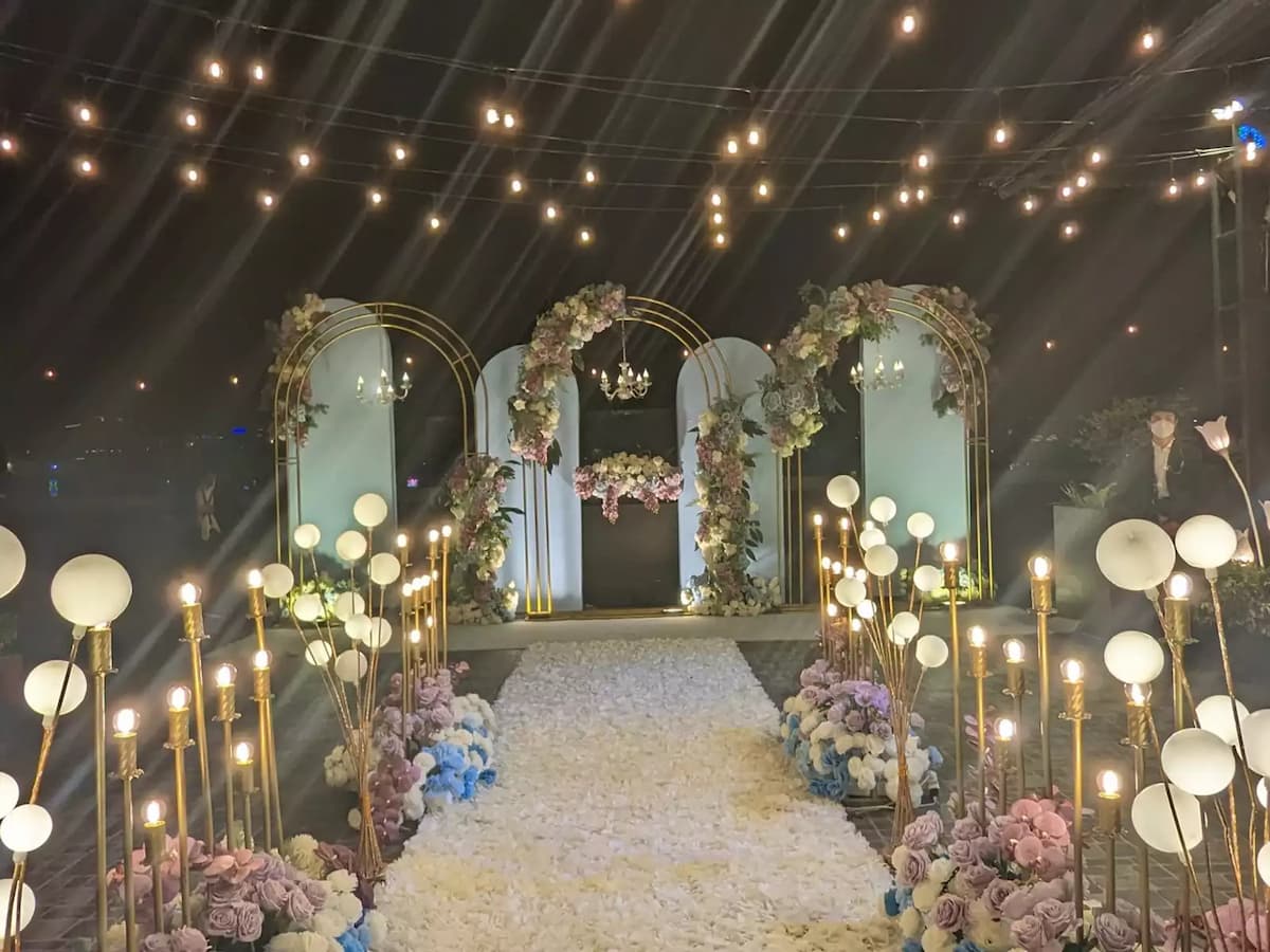 engagement event venue on rooftop with floral aisle decorated with lights and hanging fairy lights and golden floral arbour