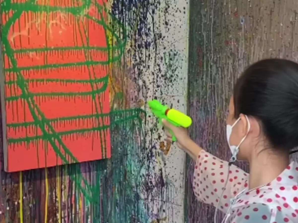 kid splattering green paint on an orange easel