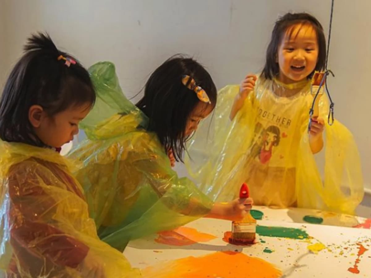childrean motion painting with paint while wearing ponchos