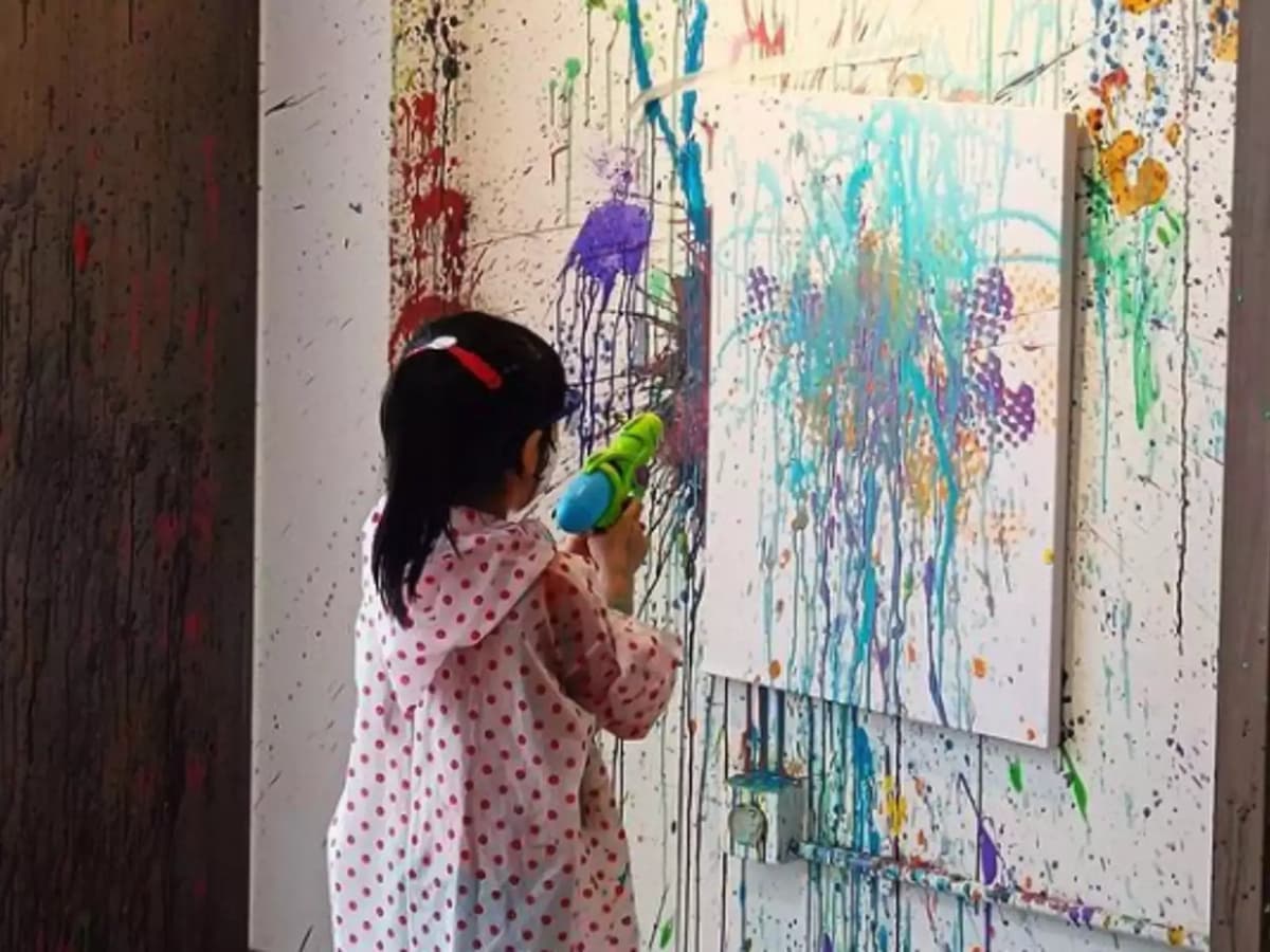 kid splattering paint on an easel
