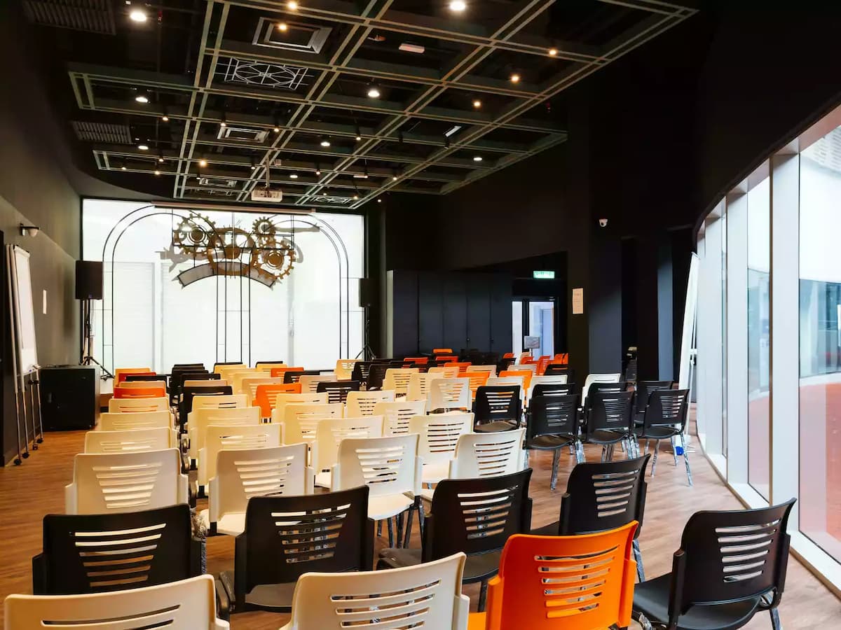 chairs facing projector and stage in room with natural lighting