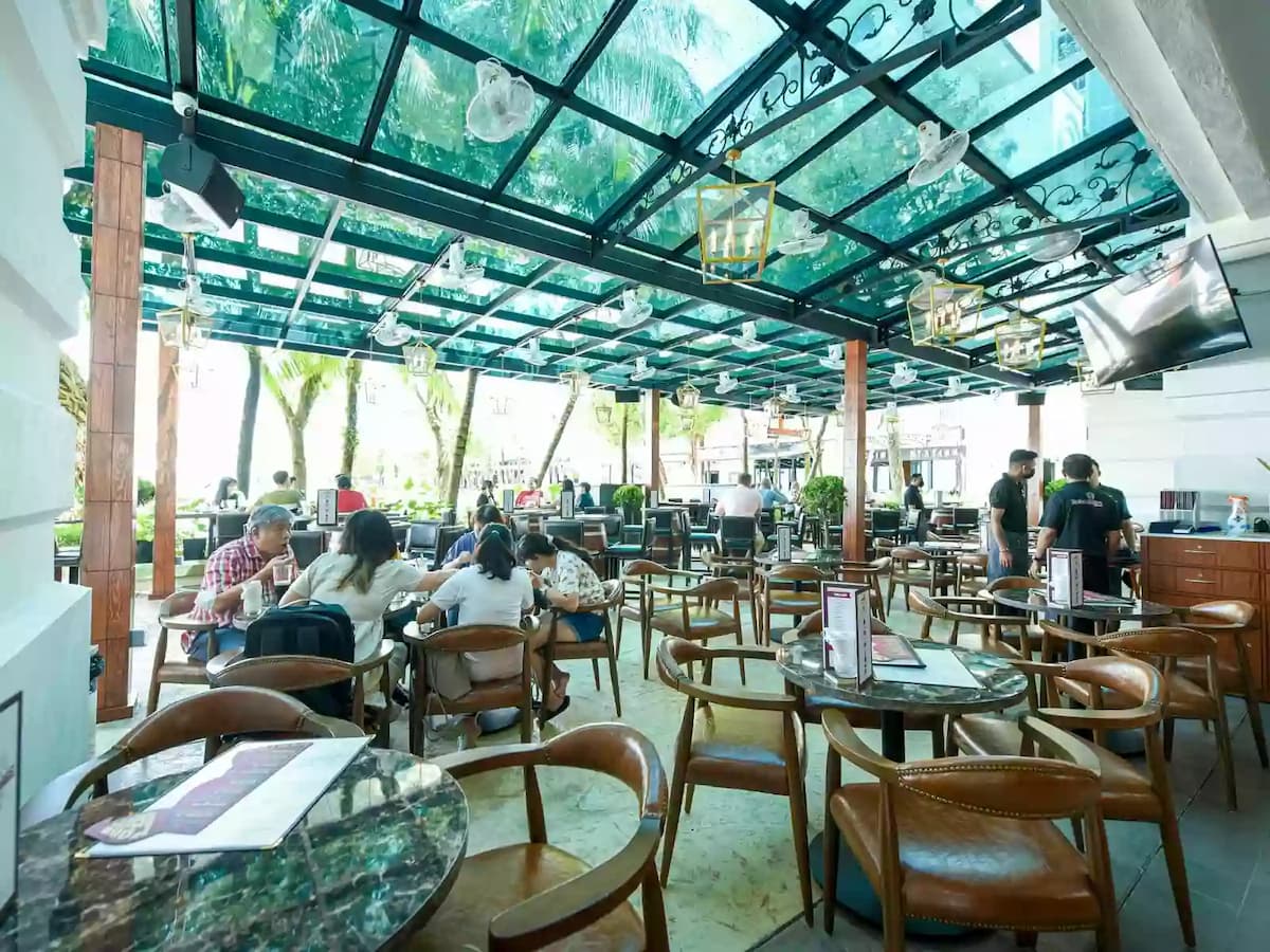 an outdoor restaurant with wooden chairs and people dining