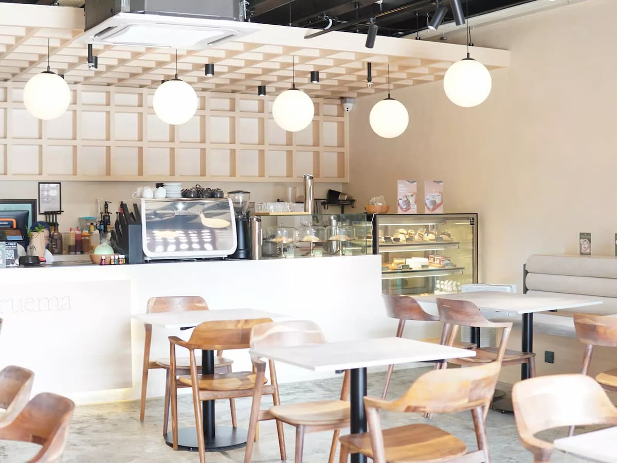 cafe interior featuring a coffee counter with wooden chairs and globe lighting at ruema cafe in kuala lumpur