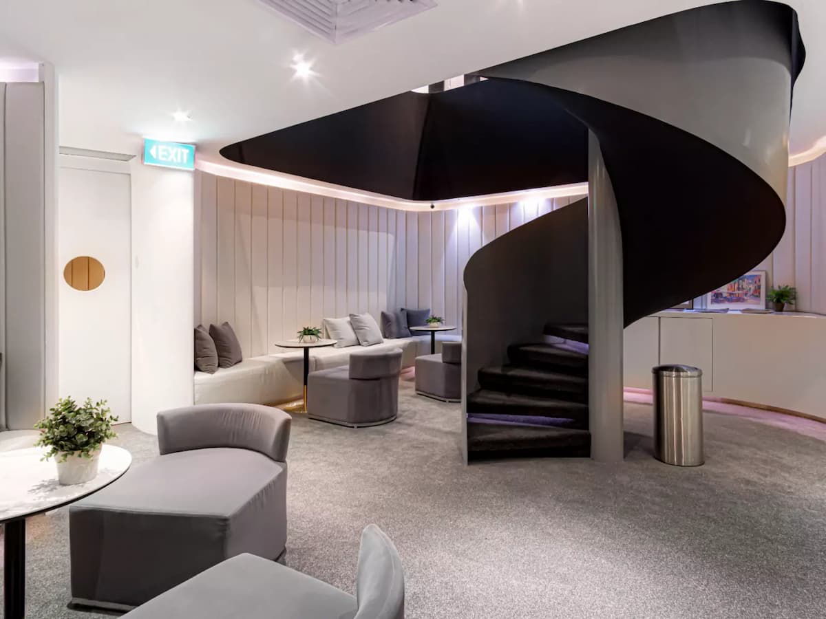 a modern lounge area with a sleek, spiral staircase in the center