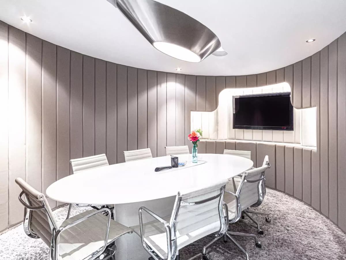 a sleek and modern meeting room with a round white table surrounded by ergonomic chairs