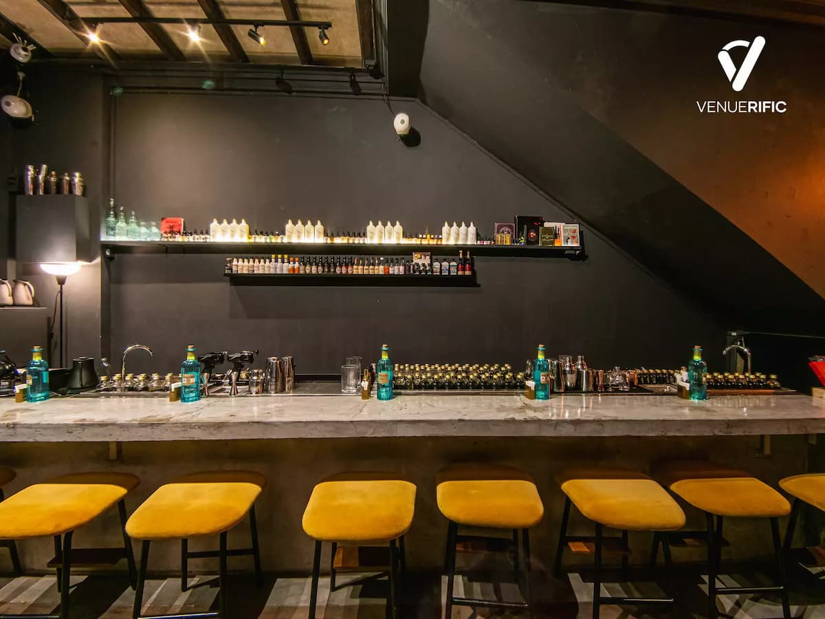 sleek bar counter with yellow stools and shelves of bottles