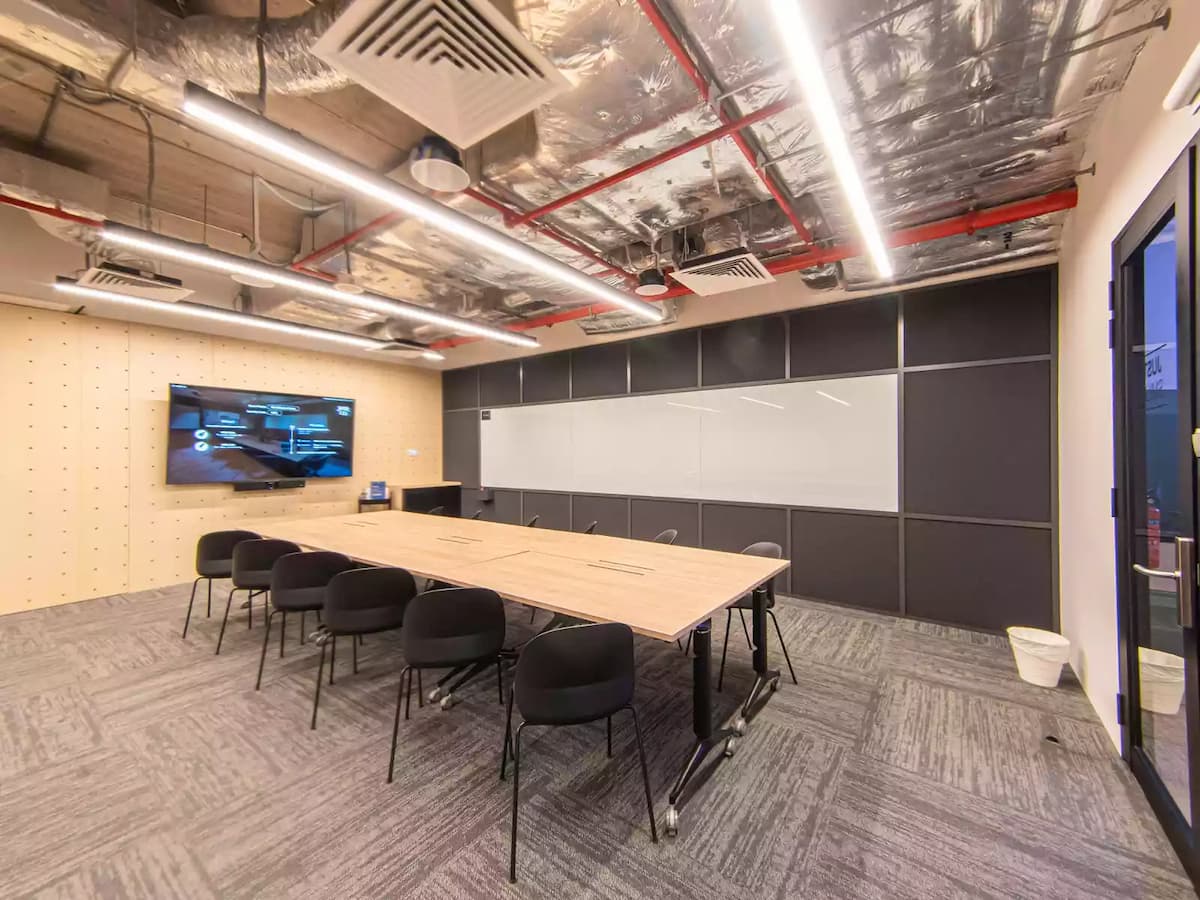 modern and well-equipped meeting room with a large table, chairs, a whiteboard, and a screen