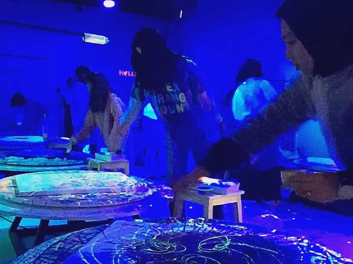 people creating art in a dimly lit room illuminated by blue and neon lights
