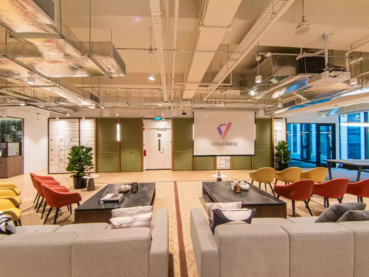 a contemporary open concept event space with multiple seating areas and a projector screen
