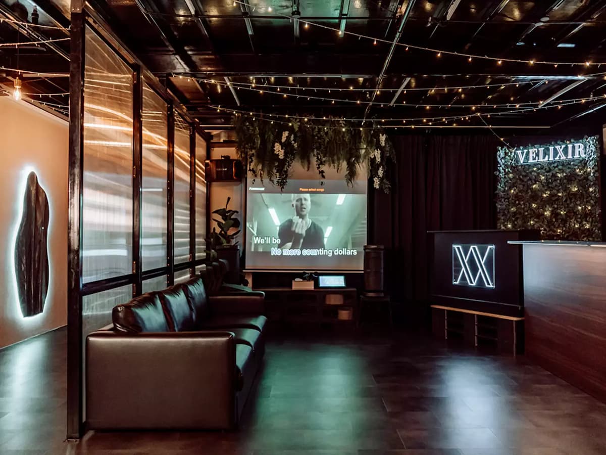 karaoke lounge with black leather sofas, a large projection screen displaying song lyrics