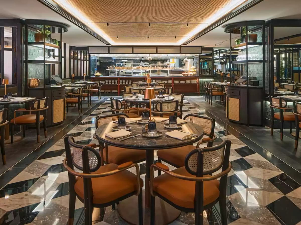 a sophisticated restaurant with marble tables, stylish chairs, and a sleek open kitchen