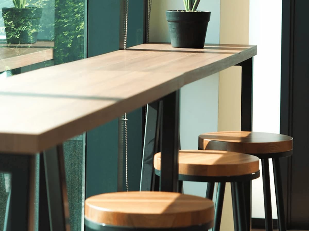 a minimalistic and cozy high-top table setup with wooden stools