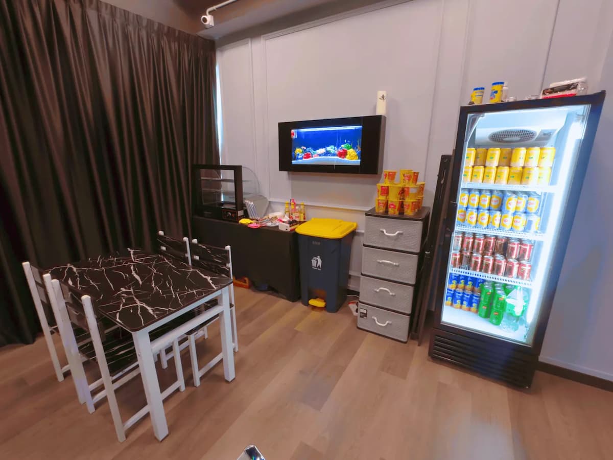 pantry area with a table and chairs, a chiller and several cup of instant noodles