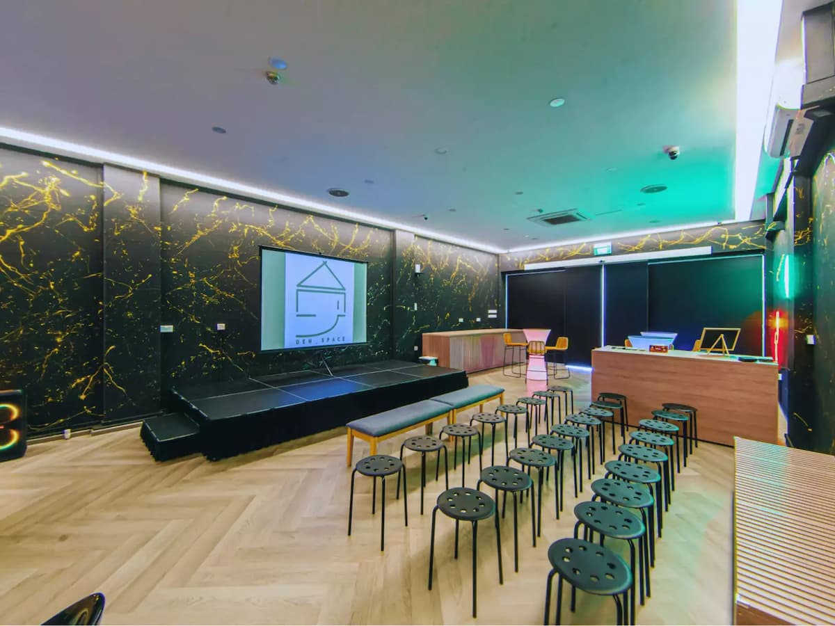 Modern event lounge with presentation stage and casual audience seating.