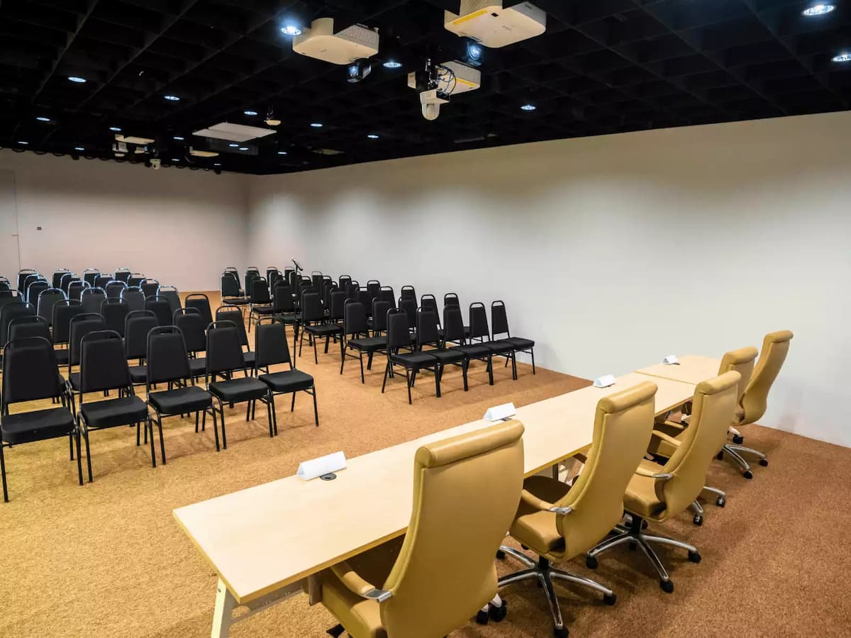 a long table with five beige office chairs arranged for panelists and row of chairs