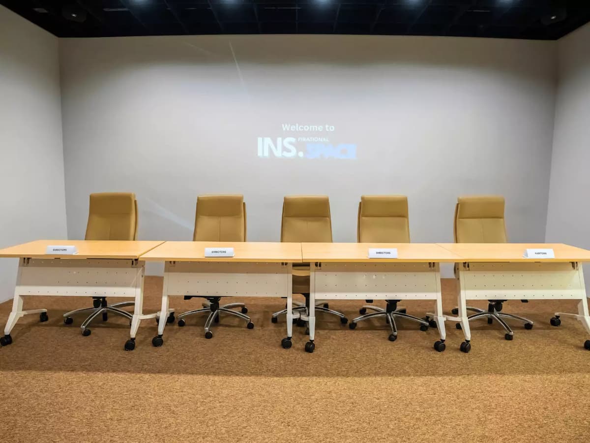 panel discussion setup with five beige office chairs arranged behind two long tables