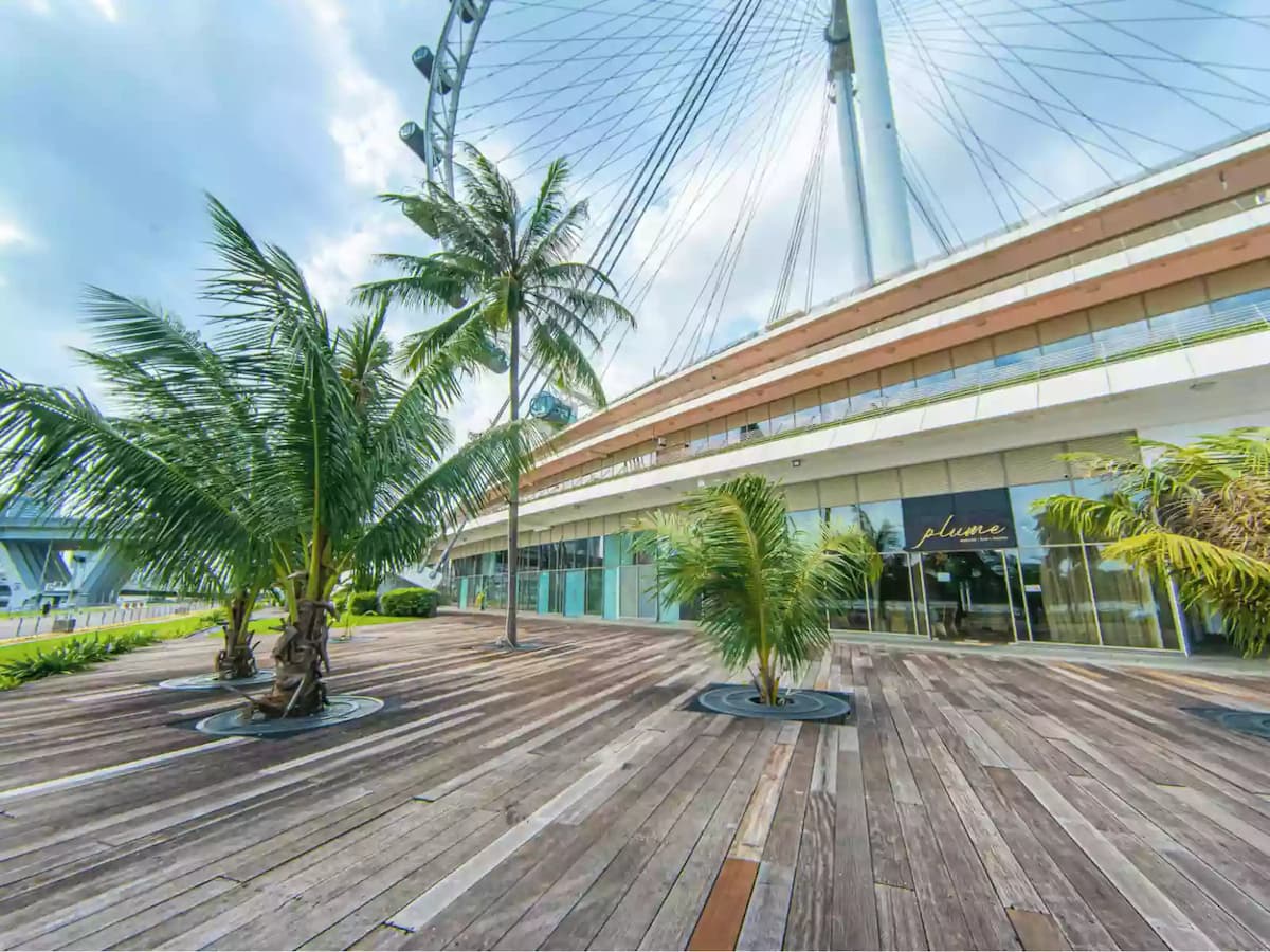 beautiful outdoor wooden deck surrounded by lush palm trees, set against the backdrop of the iconic Singapore Flyer