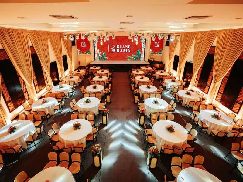 a grand banquet hall set up featuring round tables with floral centerpieces