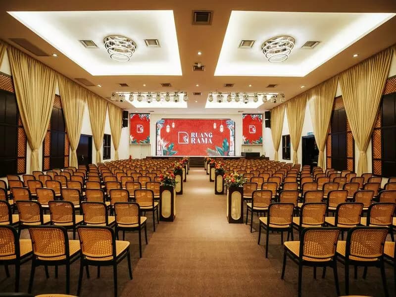 a grand event hall set up in a theater-style arrangement with elegant cane-back chairs