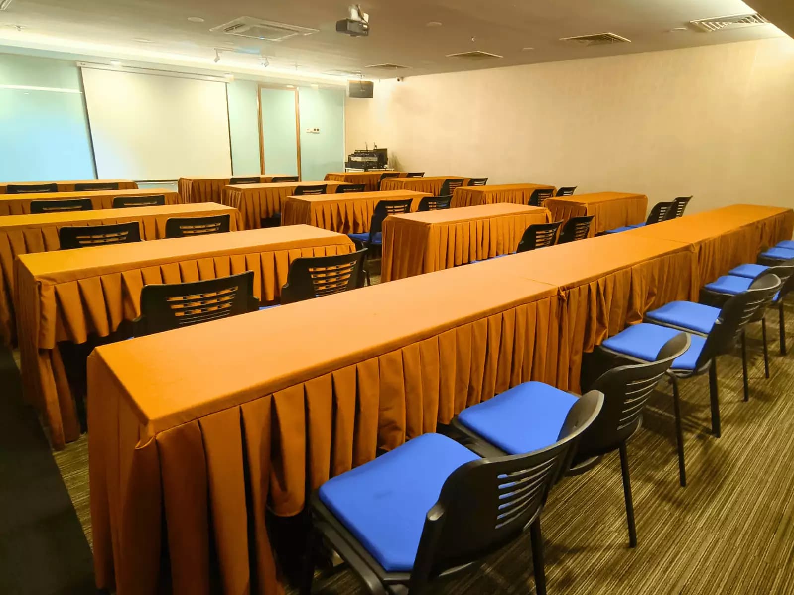 long tables draped in orange tablecloths and paired with black chairs with blue cushions