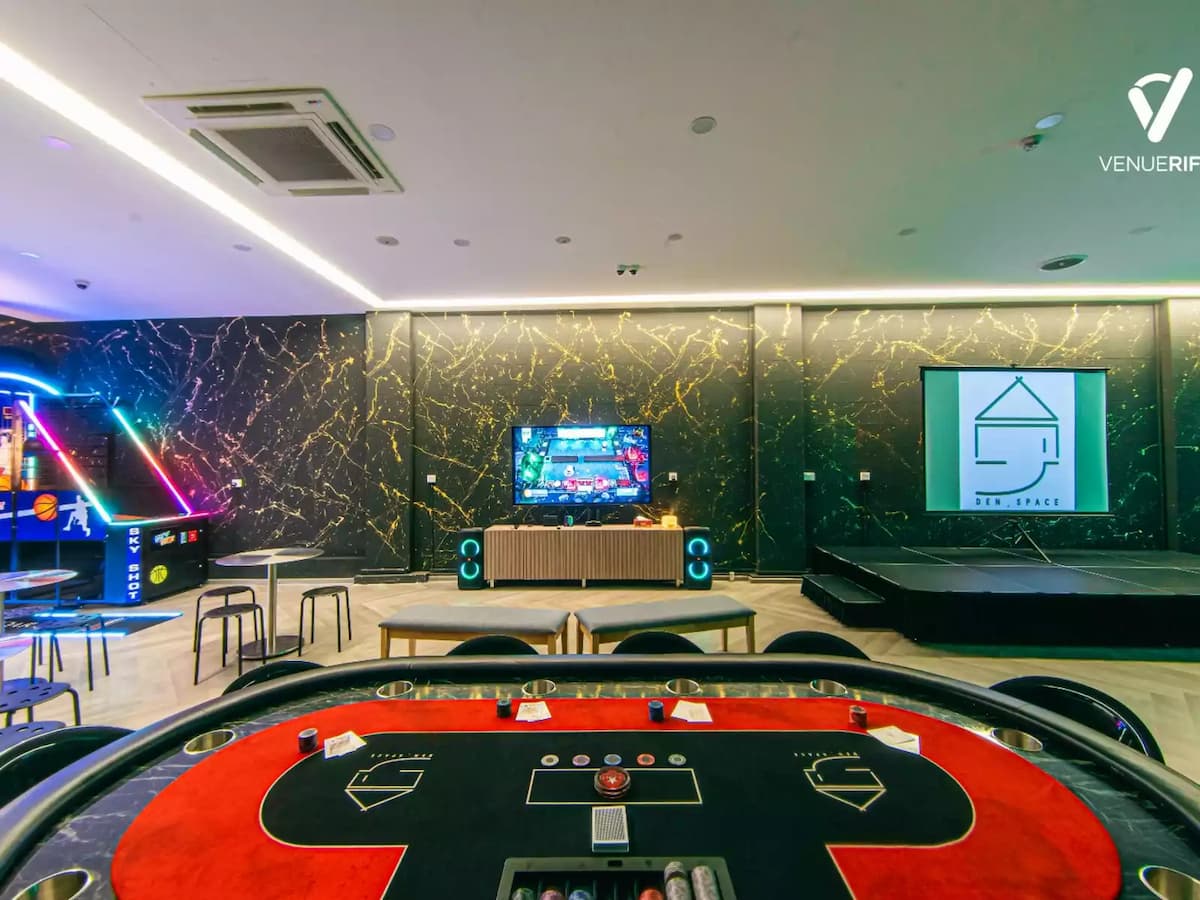 Modern entertainment lounge with poker table, arcade games, and presentation stage.