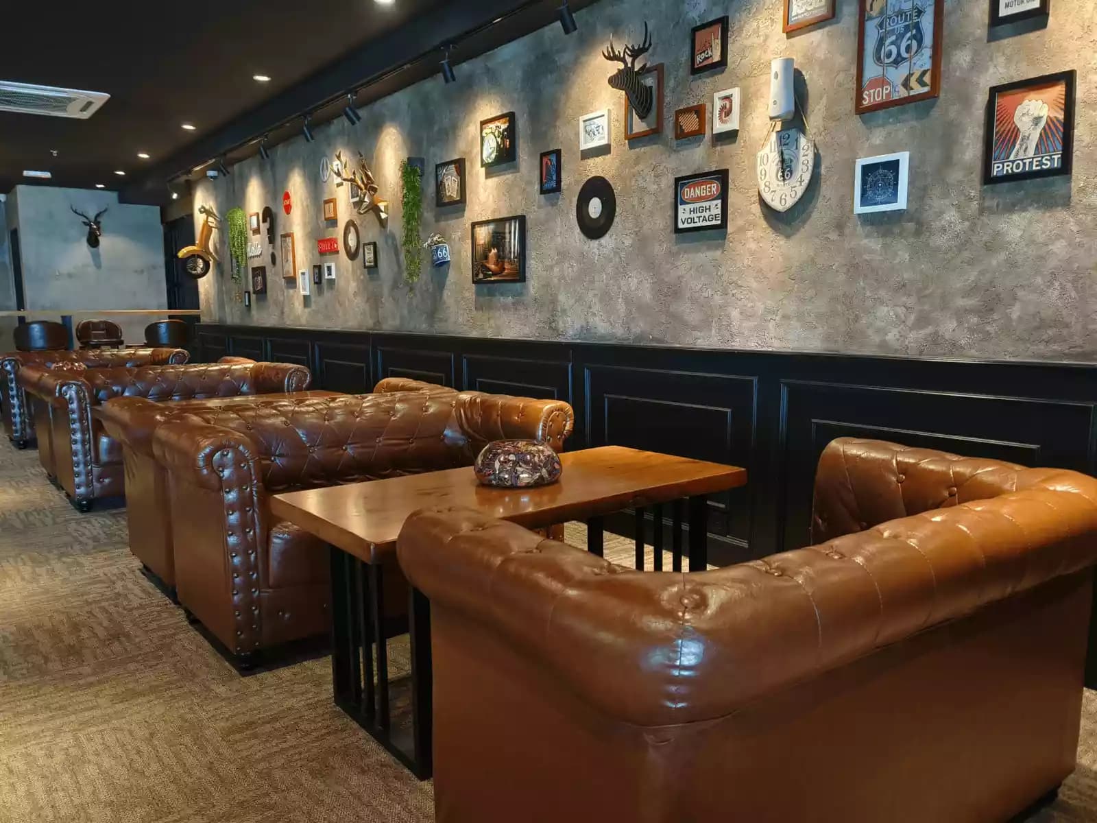 A cozy lounge with vintage-inspired décor, featuring plush brown leather sofas and wooden tables