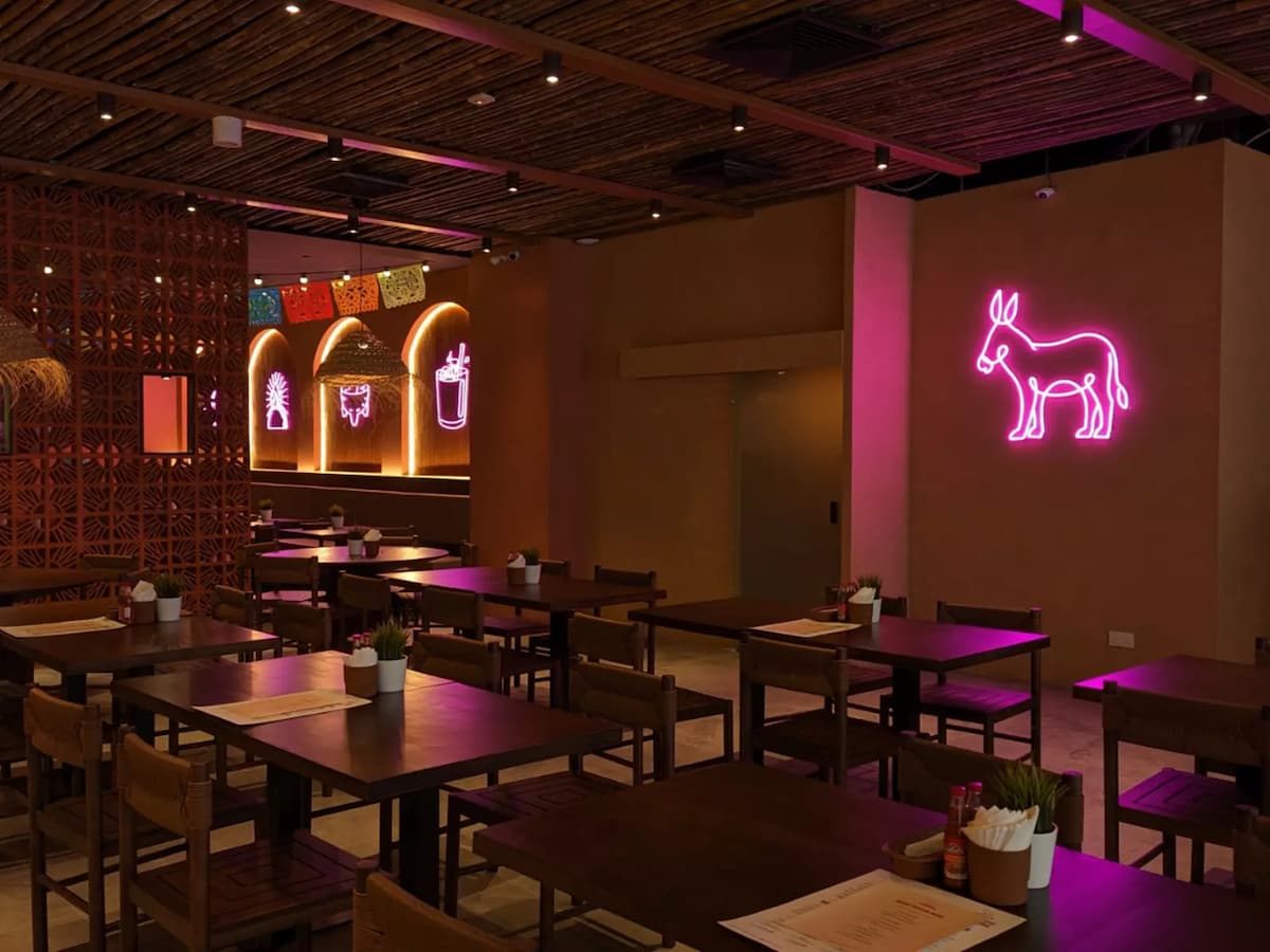 A spacious dining area featuring rustic decor, wooden furniture, and playful neon art