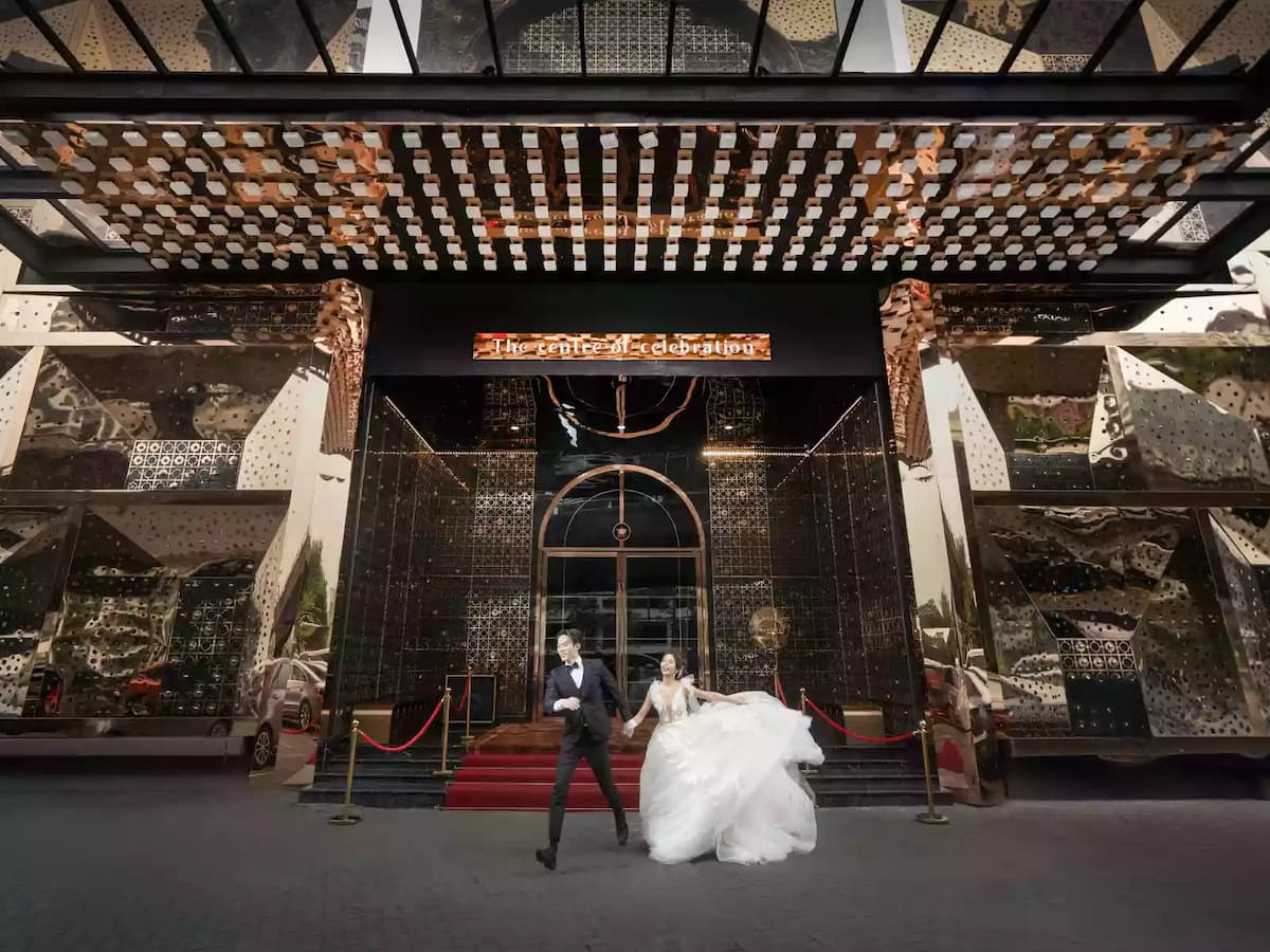 A glamorous couple in wedding attire poses playfully outside