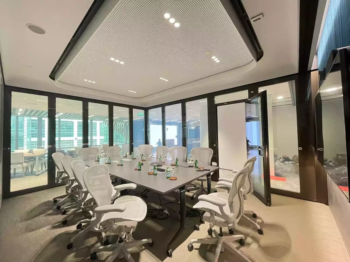Modern executive meeting room with conference table, ergonomic chairs, and glass walls.