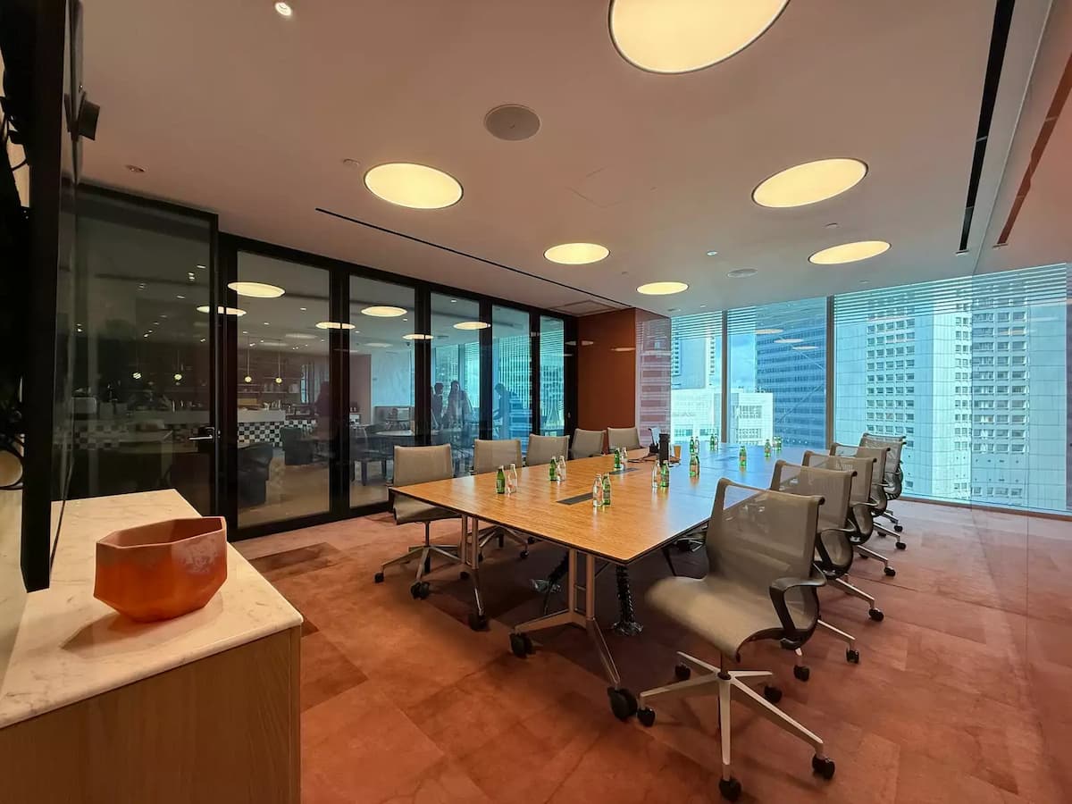 Executive meeting room with collaborative table setup, ergonomic chairs, and city skyline views.