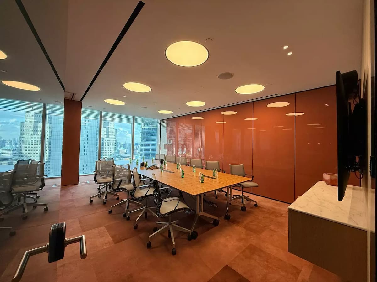 Executive meeting room with collaborative table setup, ergonomic chairs, and city views.