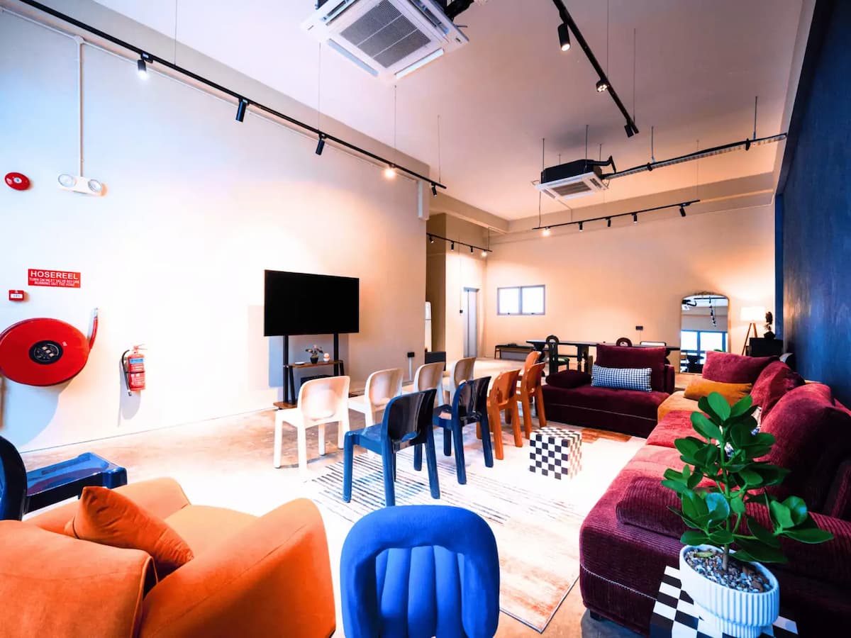 Colorful seminar-style event setup with TV screen, lounge seating, and eclectic decor