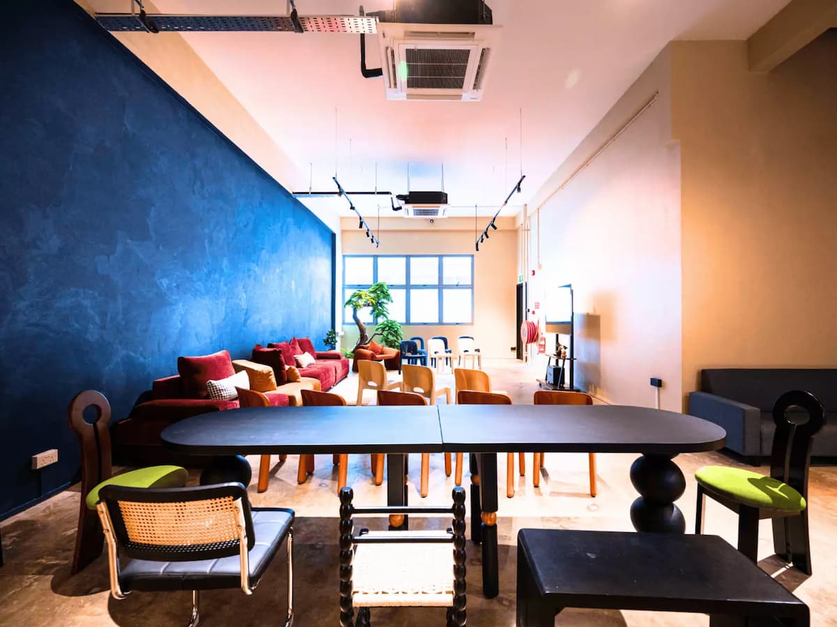 Modern event space with eclectic seating, long black table, and blue feature wall